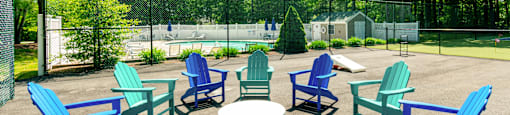 Outdoor Fire Pit with blue and green chairs are arranged in a circle at Mariner's Hill Apartments, Massachusetts.