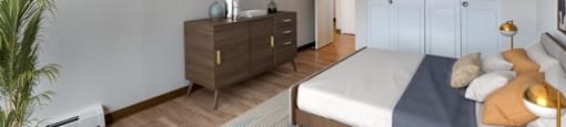 A bedroom with a bed, dresser, and a potted plant.
