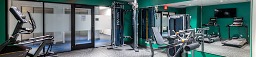 a gym with exercise equipment and mirrors in a building with green walls  at 140 Clarendon, Massachusetts, 02116