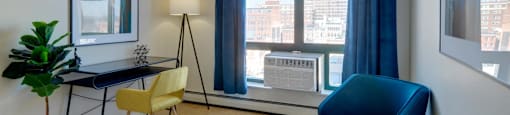 Home office with a blue chair and a desk and a window at Ninth Square Apartments. at Ninth Square Apartments, New Haven