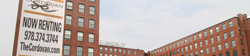 A large brick building with a sign that says "Cordovan Now Renting".