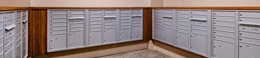 A row of grey lockers are lined up against a wall with two framed pictures hanging above them.