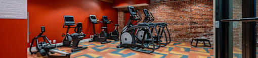 A gym with a variety of exercise equipment and a colorful floor.