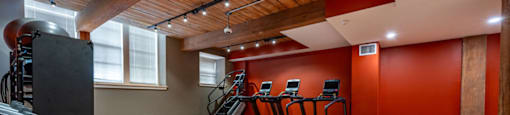 A gym with a wooden ceiling and a treadmill.