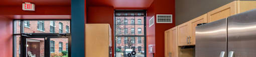 A kitchen with a red wall and a stainless steel refrigerator.