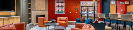 A room with orange chairs and a television on the wall.