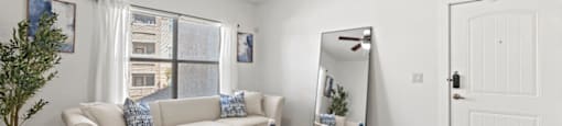 A living room with a beige couch, a blue rug, and a ceiling fan.