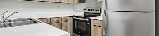 A modern kitchen with a stainless steel refrigerator, sink, and oven.