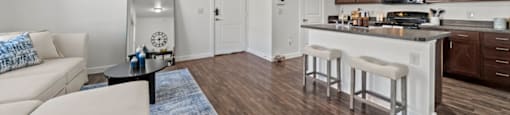 A modern kitchen with white cabinets and a wooden floor.