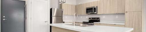 A modern kitchen with a white countertop and wooden cabinets.