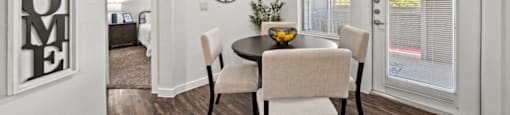 A dining room with a table set for two and a welcome sign on the wall.