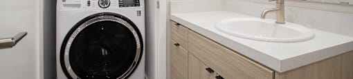 A white front loading washing machine in a small bathroom.