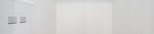 A white closet with a door and a shelf above it.