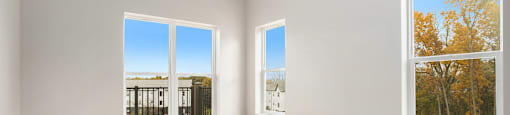 A room with two windows, one of which shows a view of trees.