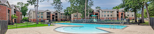 A swimming pool surrounded by a concrete patio and trees.