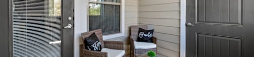 A patio with a chair and a table with a pillow on it.