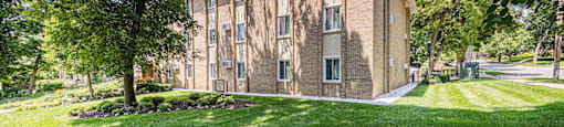 a brick building with trees and grass in front of it