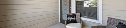A small balcony with a couch, chair, and potted plant.