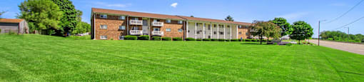 a large brick building with a green lawn in front of it