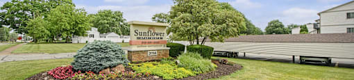 the sign is in the middle of a yard with flowers and plants