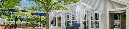 a patio with a tree and a white house