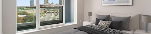 a bedroom with a bed and a large window with a city view