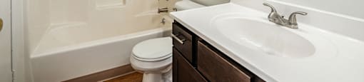 A white bathroom with a toilet, sink, and shower.