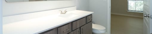 A bathroom with a white counter top and a white toilet.