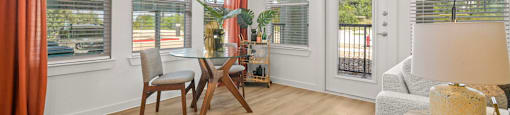 A room with a table, chairs, and a view of the outside through the windows.