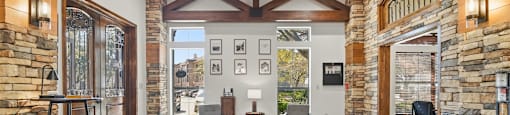 A spacious living room with a stone wall and wooden ceiling.