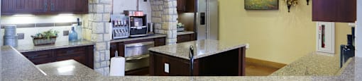 A kitchen with a stone archway and a refrigerator.