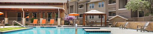 A large swimming pool in front of a building with a sun lounger.