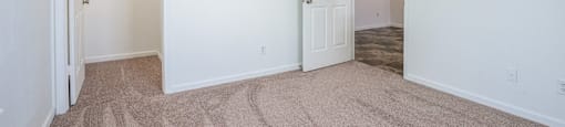 a bedroom with white walls and carpet