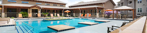 A large outdoor swimming pool with a diving board and a building in the background.