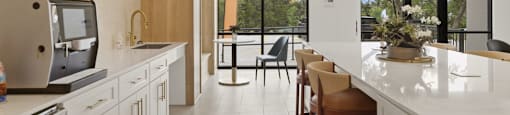 A kitchen with a white counter top and wooden chairs.