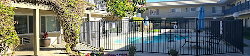 A pool surrounded by a black fence and a green lawn.