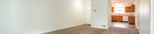 A large, empty room with carpeted flooring and white walls.