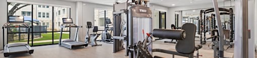 A gym with a treadmill, elliptical machines and other exercise equipment.