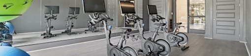 A gym with exercise bikes and a fan.