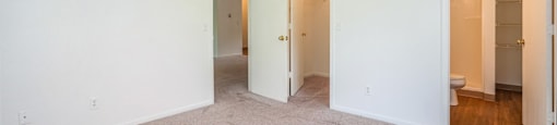 a bedroom with white walls and carpet