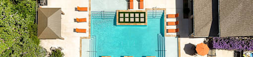 An aerial view of a pool surrounded by orange chairs and green plants.