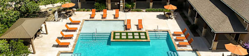 A large swimming pool surrounded by orange lounge chairs and umbrellas.