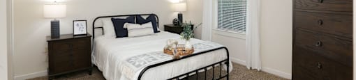 A bedroom with a bed, dresser, and ceiling fan.