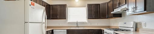 a kitchen with dark wood cabinets and white appliances