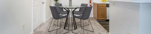 a dining area with a glass table and chairs and a kitchen