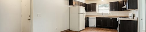 A kitchen with a refrigerator, cabinets, and a counter.