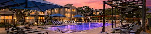 A beautiful outdoor swimming pool area with lounge chairs and a pergola.