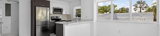A kitchen with a refrigerator, microwave, and sink.