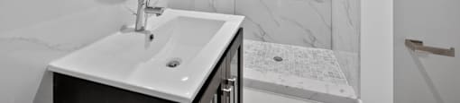 A white sink in a bathroom with a marble wall.