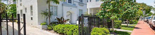 A white building with a black gate in front.